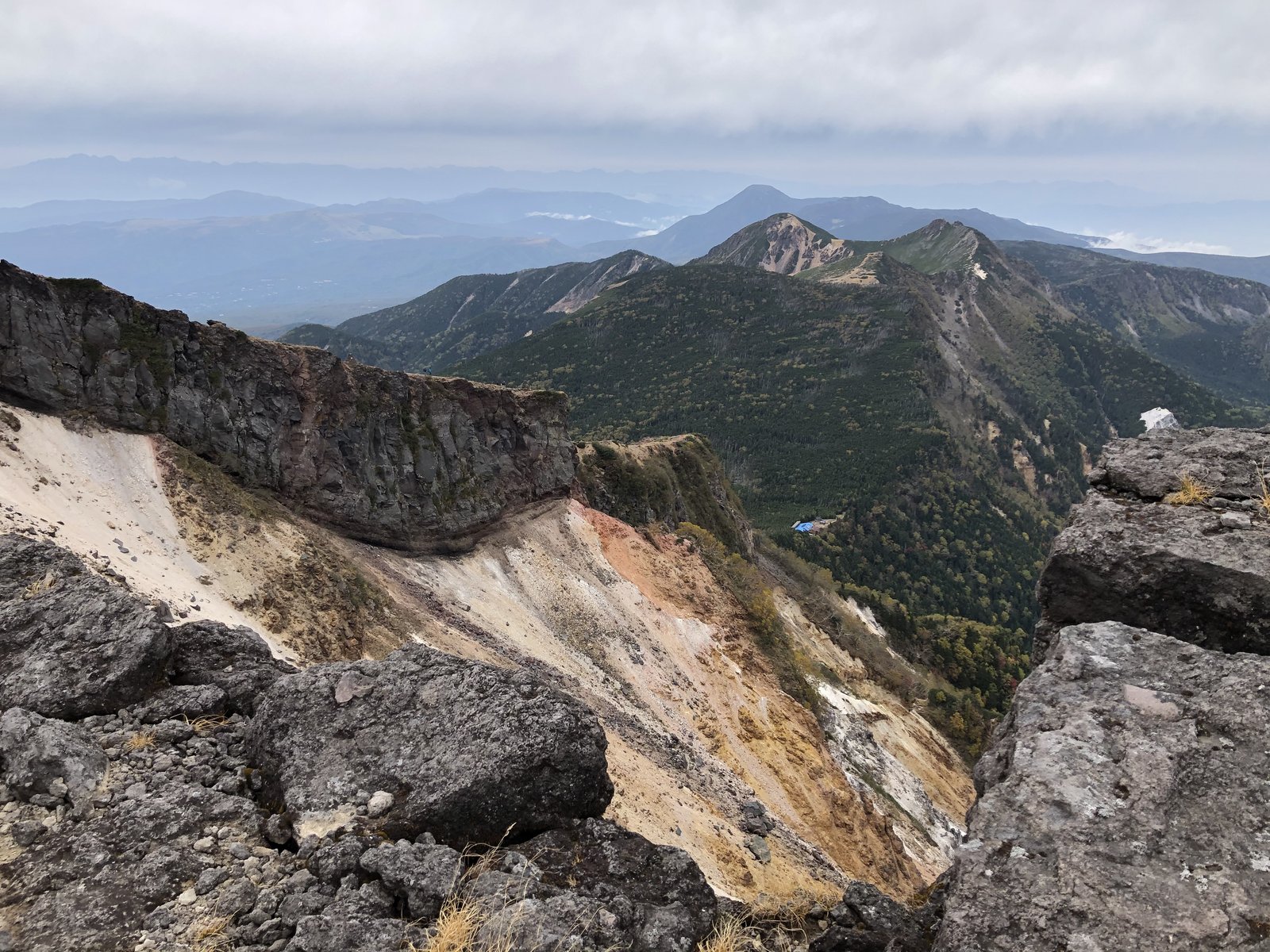 硫黄岳山頂の北側 大きくえぐれた崖と、その先に続く山並み ヤマカルテ