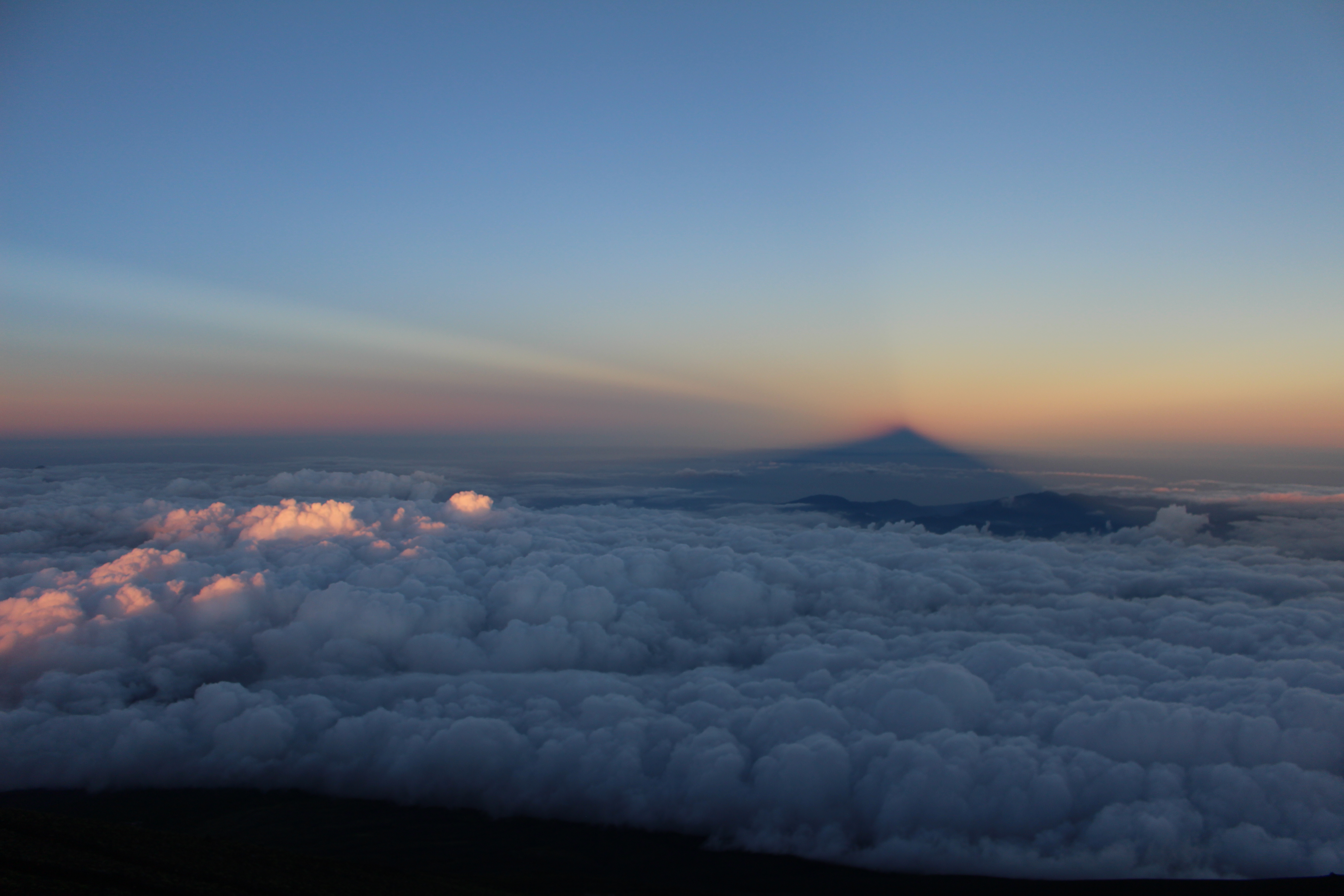 水平線越えに大気のスクリーンに映る富士山の影