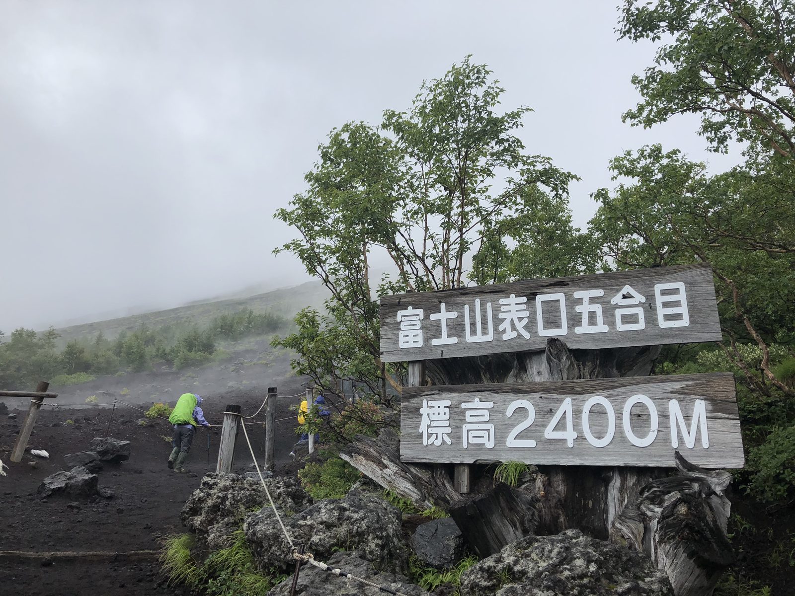 富士山表口五合目の標高2400m看板とガスに沈む登山道を登る登山者 台風接近時の富士登山