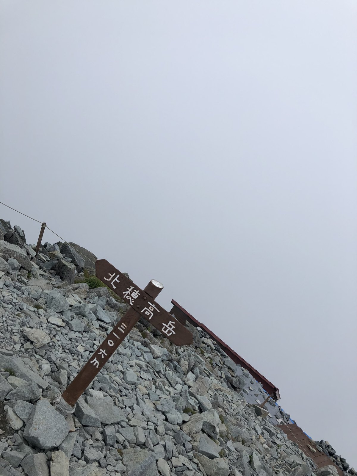 ガスに包まれた北穂高岳の山頂標識 眺望のない夏の穂高