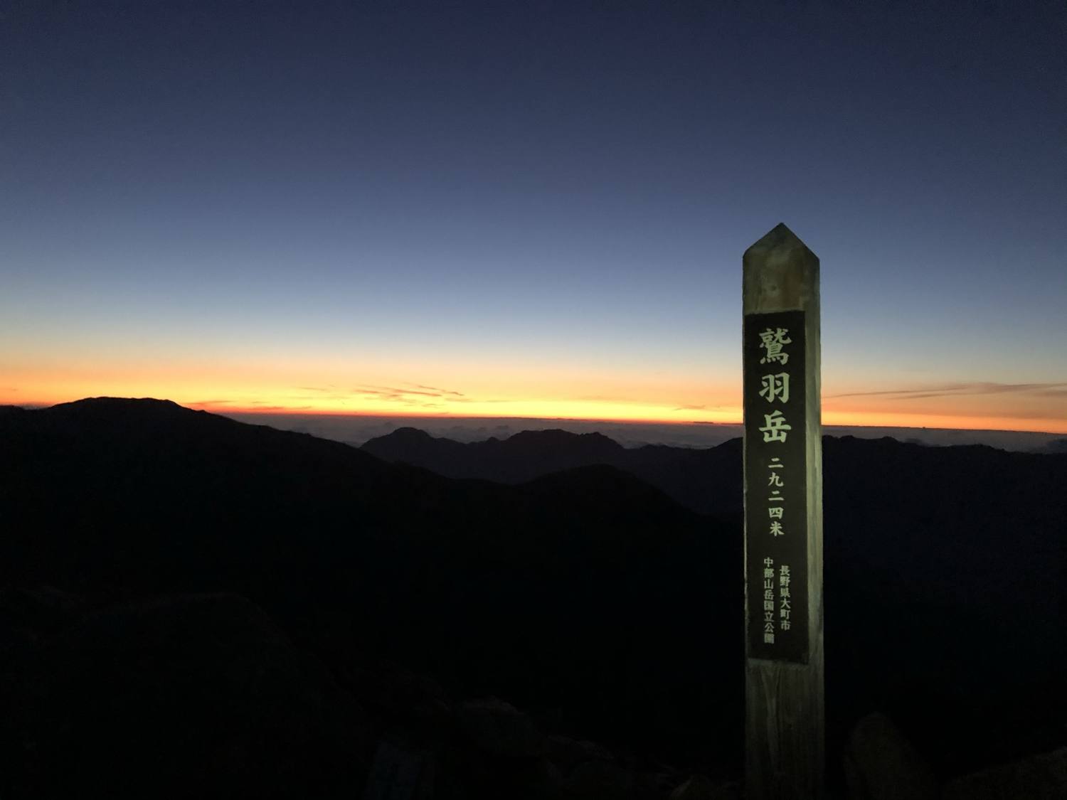 夜明け前の鷲羽岳山頂標と地平線を染める朝焼け 標高2,924m